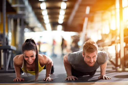 A man and woman are performing push-ups together in a gym - Chiropractor Langhorne PA A man and woman are performing push-ups together in a gym - Chiropractor Langhorne PA