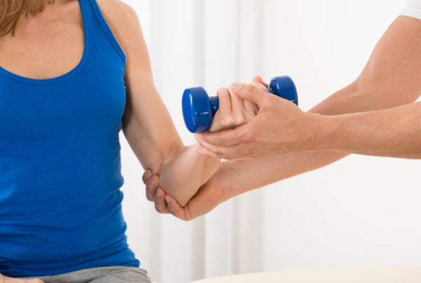 A therapist supporting a patient’s arm during a light dumbbell exercise to enhance joint alignment and mobility - Extremity Adjusting
